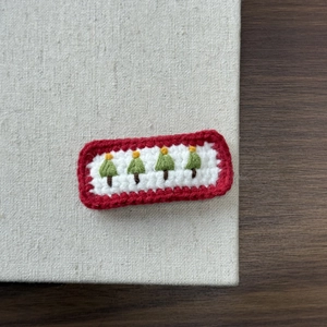 Detail of handcrafted knitted Christmas tree hair clip with festive red and green colors