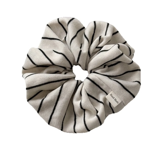 Knitted black and white striped hair scrunchie with a handmade label on white background