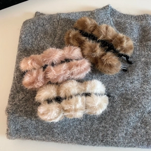 Pinces banane en peluche marron, rose et blanc sur fond en maille grise douce