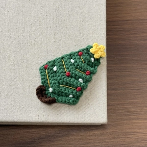 Nahaufnahme einer handgehäkelten Tannenbaum-Haarklammer mit roten und weißen Details