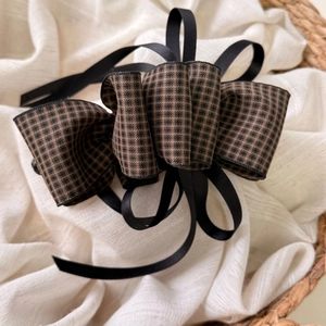Close-up of elegant houndstooth ribbon bow banana clip on rustic linen background