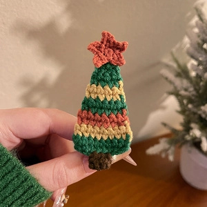 Gros plan d'une pince à cheveux sapin de Noël au crochet fait main avec texture verte et rouge