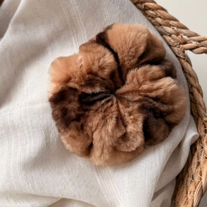 Gros plan d'un chouchou en fausse fourrure douce avec dégradé de marron sur tissu blanc
