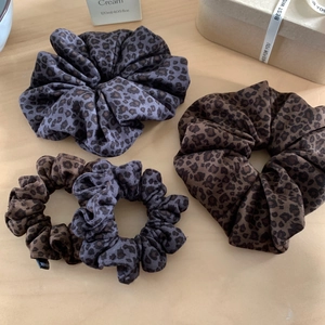 Set di elastici per capelli leopardati nei toni marrone e grigio su fondo legno