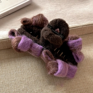 Macro shot of fluffy plush hair claw clip with dark coffee and purple yarn texture detail