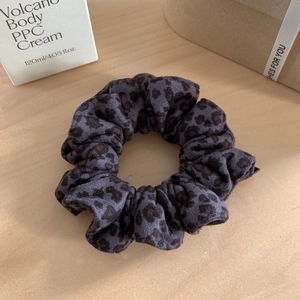 Dettaglio di elastico per capelli leopardato grigio con texture morbida in velluto