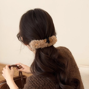 Dettaglio di un fermaglio per capelli in peluche con un orsetto e un fiocco nero decorativo