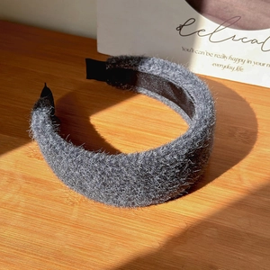 Detailed view of dark grey plush sponge headband on a textured wooden background