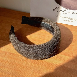 Close-up of thick fuzzy woolen headband with soft plush texture on a wooden surface
