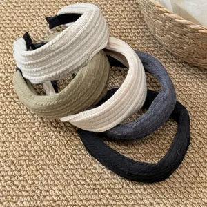 Cinq bandeaux en tricot torsadé rétro aux couleurs neutres posés sur un tapis en jute naturel