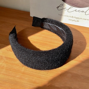 Close-up of black velvet padded headband on a wooden surface with natural light