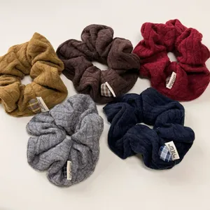 Detailed view of knitted hair scrunchies in five retro colors with rib texture and NEW label