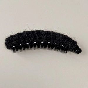 Dettaglio del fermaglio a banana in pelliccia sintetica nera con denti in plastica sicuri