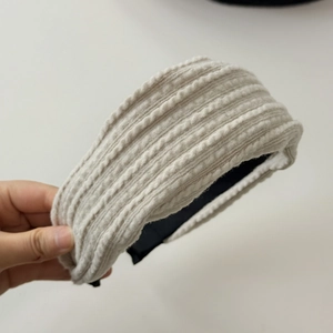 Vue détaillée du bandeau tricoté beige avec une texture épaisse à rayures horizontales
