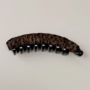 Dettaglio della trama leopardata in tessuto e dei denti in plastica della clip banana