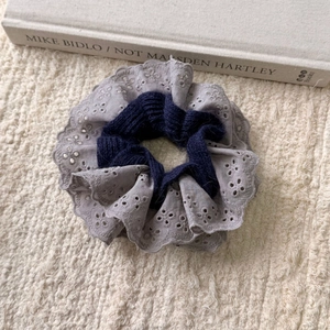 Detailed close-up of retro lace embroidery and blue cable knit texture hair scrunchie