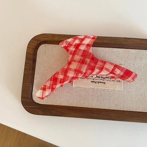 Vintage red gingham hair claw clip with red bead accents in a rustic wooden tray
