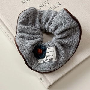 Detailed view of grey knitted hair scrunchie with leopard edge and floral patch detail