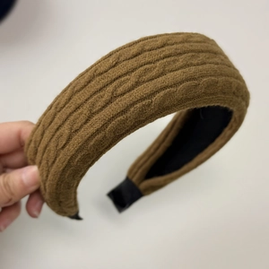 Detail of a brown thick knitted headband showing twisted braid texture and black lining