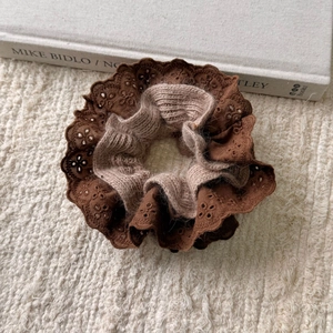 Detail of dark brown lace embroidery and light brown knit fabric on the oversized scrunchie