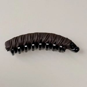 Dettaglio della texture in pelle marrone a pieghe di un elegante fermaglio a banana