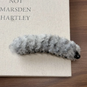 Gros plan sur la texture en peluche grise et les dents de la pince banane en fausse fourrure