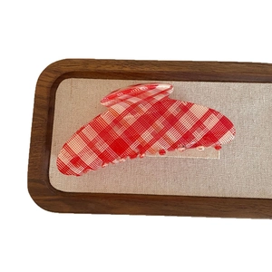 Vintage red and white checkered hair claw clip displayed on a wooden tray with linen lining