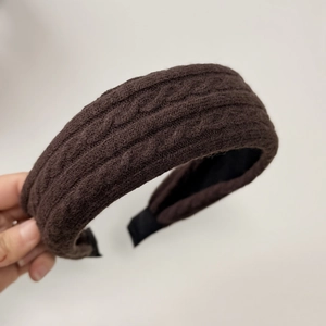 Close-up of dark brown cable knit headband with thick yarn texture and black lining