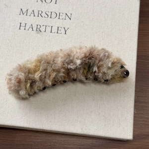 Détail de la pince banane en peluche avec texture en fausse fourrure et perles noires