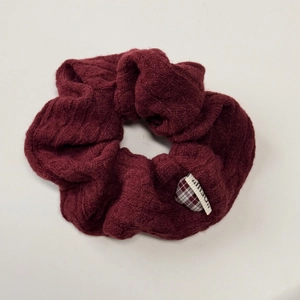 Close-up of burgundy cable knit headband featuring thick ribbed texture and small fabric label