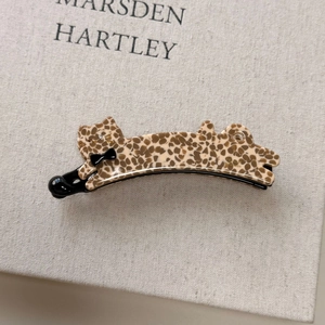 Detail of leopard print acetate cat hair clip with black bow and handmade logo