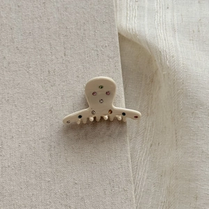 Detail view of small cream acetate hair claw clip with colorful rhinestones inlay