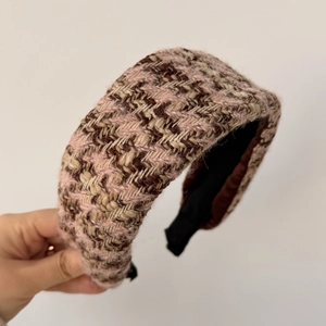 Nahaufnahme eines gepolsterten Tweed-Haarreifens in Rosa und Braun mit Webstruktur
