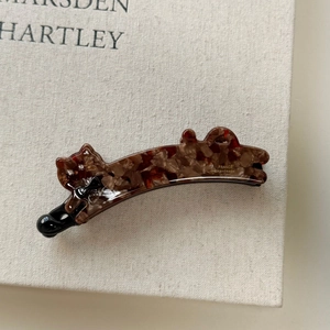 Close-up of tortoise shell cat hair clip with small crystals and a black bow accent