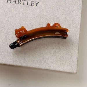 Detail of a handmade tortoise shell cat hair clip with sparkling eyes and a black bow