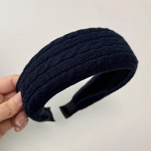 Detail of dark blue cable knit headband showing thick braided texture and inner lining