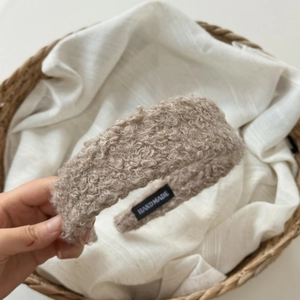 Detailed macro view of beige sherpa headband featuring black handmade textile label