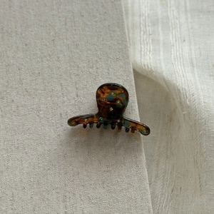 Close-up of mini tortoiseshell acetate hair claw clip with colorful rhinestone inlay