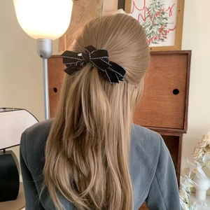 Elegant black velvet bow hair clip with white polka dot edges shown on long hair