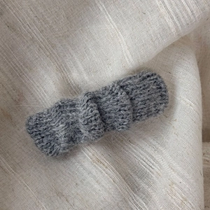 Close-up detail of grey knitted mohair hair clip texture on a rustic linen background