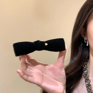 Elegant vintage black velvet bow hair clip with gold metal buckle held by hand