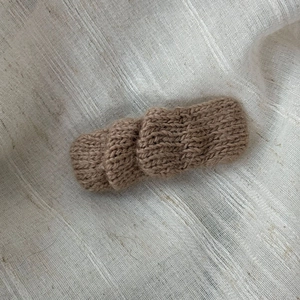Detail of warm caramel knit hair clip with soft wool texture on linen background