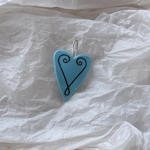 Detail view of a bright blue heart hair clip with black swirl patterns and silver metal clasp