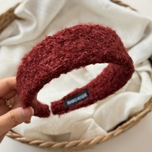 Close-up of wine red fuzzy headband with soft curly fleece texture and handmade label