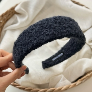 Detail view of handmade black plush wide headband with wool-like texture and brand label