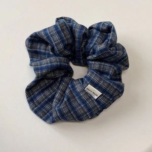 Detailed close-up of blue plaid fabric headband featuring a white Hand Made label