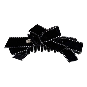 Elegant black velvet bow hair claw clip with white polka dot stitching on white background