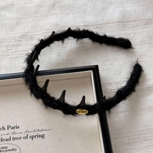 Detailed macro view of black faux fur headband with gold metal tag and punk spikes