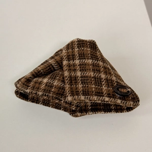 Détail de la pince à cheveux en tweed avec motif à carreaux bruns et bouton décoratif