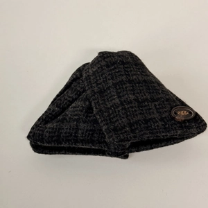 Détail de la pince à cheveux en tricot gris foncé avec motif à carreaux et bouton décoratif